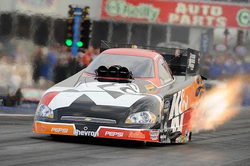 Drag racing car blowing fire out of exhaust as it takes off