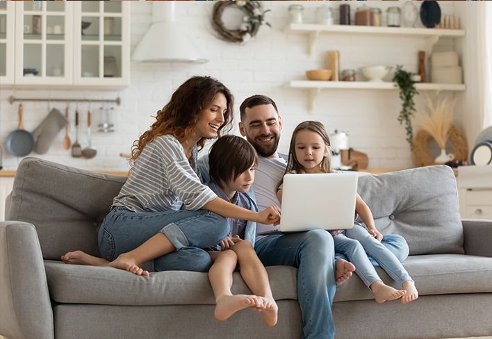 Family on a new Couch looking at a laptop together