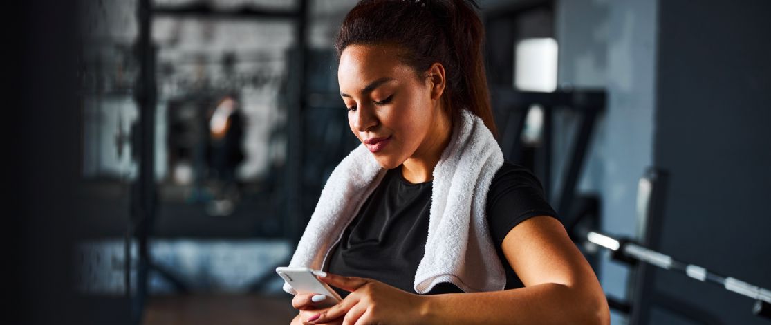 Woman in the gym using her phone after a workout