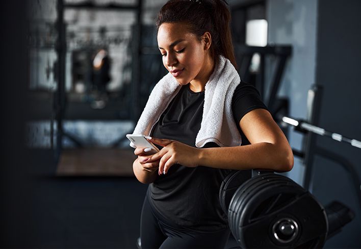 Woman in the gym using her phone after a workout