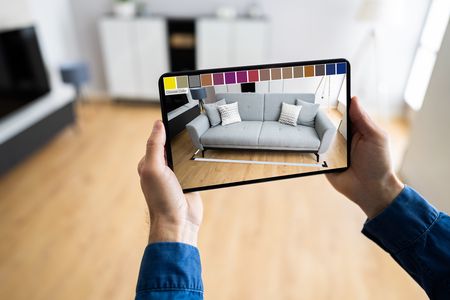 Person using a tablet to position a couch in augmented reality