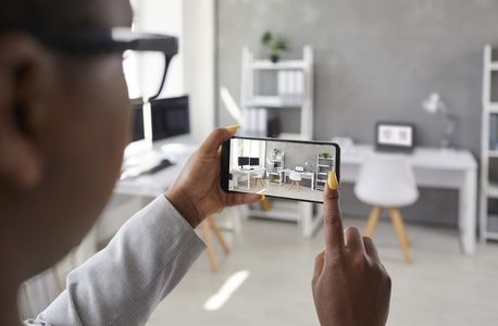 Man using his phone to photograph his home office area