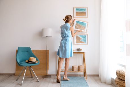 Woman adjusting new artwork on the wall in a new home