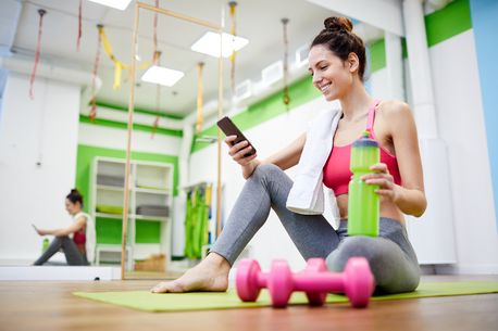 Woman using her phone after a working in a gym classroom