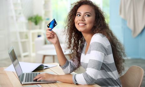 Woman at a laptop with her credit card purchasing items online